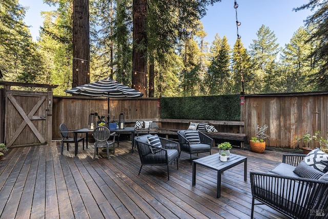 wooden deck featuring a gate, an outdoor living space, and a fenced backyard