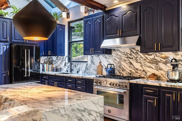 kitchen featuring a sink, high end range, under cabinet range hood, blue cabinetry, and black fridge