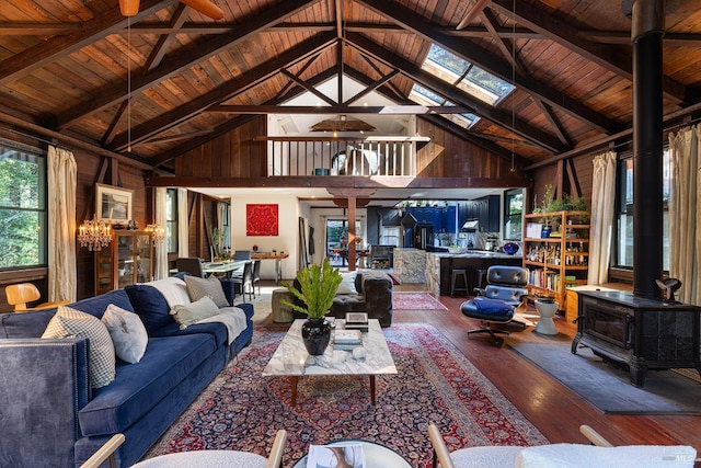 living room with a wood stove, wood walls, and high vaulted ceiling