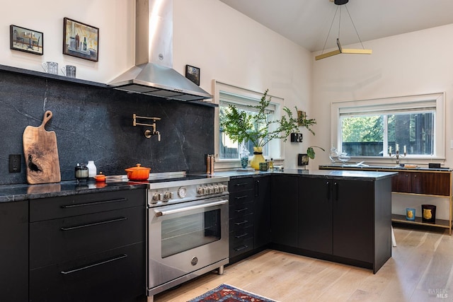 kitchen with high end range, light wood-type flooring, dark cabinets, and island exhaust hood