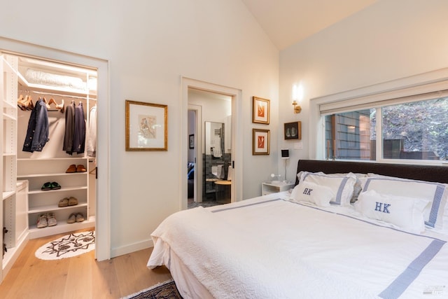 bedroom featuring wood finished floors, a closet, baseboards, a spacious closet, and high vaulted ceiling