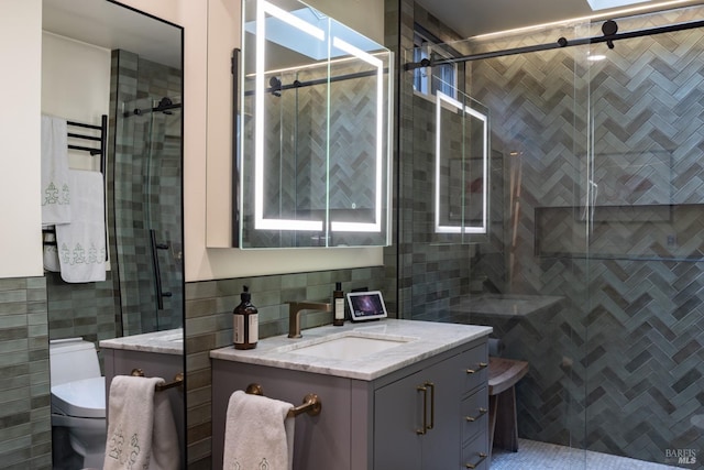 full bathroom with toilet, tile walls, a shower stall, and vanity
