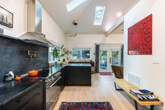 kitchen with stainless steel electric range oven, visible vents, wall chimney exhaust hood, dark cabinetry, and a skylight