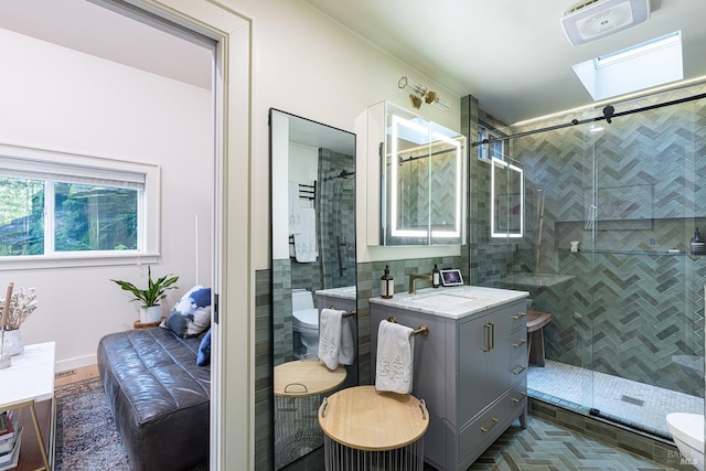 bathroom featuring toilet, vanity, a shower stall, and a skylight