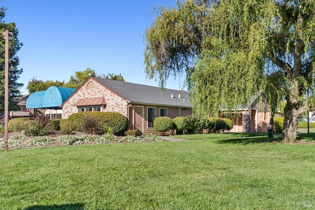 ranch-style house featuring a front yard and brick siding