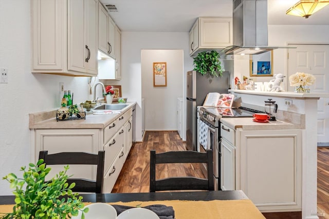 kitchen with a sink, island exhaust hood, electric range, light countertops, and wood finished floors