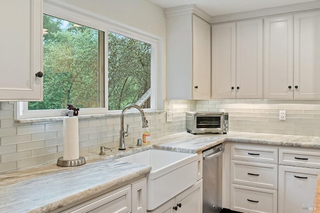 kitchen with backsplash, stainless steel dishwasher, a sink, and white cabinetry