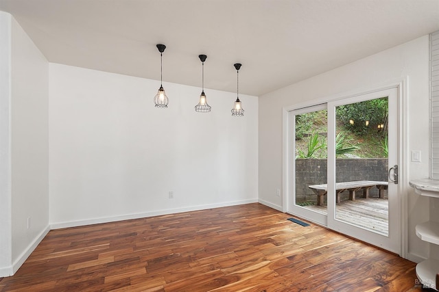 unfurnished dining area featuring visible vents, baseboards, and wood finished floors