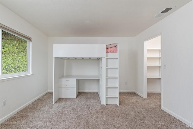 unfurnished bedroom featuring visible vents, baseboards, a closet, and light colored carpet