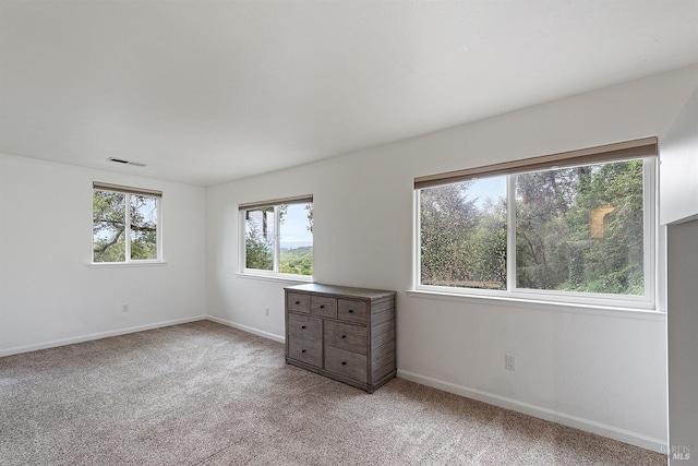 unfurnished room with visible vents, light colored carpet, and baseboards