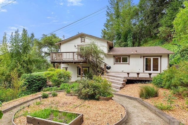 rear view of house featuring a vegetable garden and a wooden deck