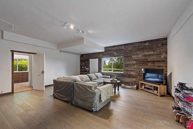 living room featuring wooden walls, hardwood / wood-style flooring, and baseboards