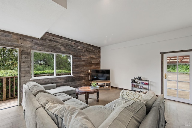 living area with plenty of natural light, wooden walls, and hardwood / wood-style floors