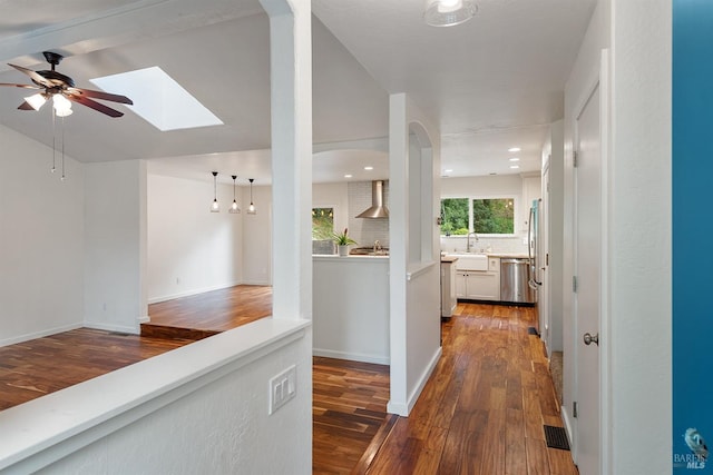 hallway with baseboards, dark wood-style floors, visible vents, and lofted ceiling with skylight