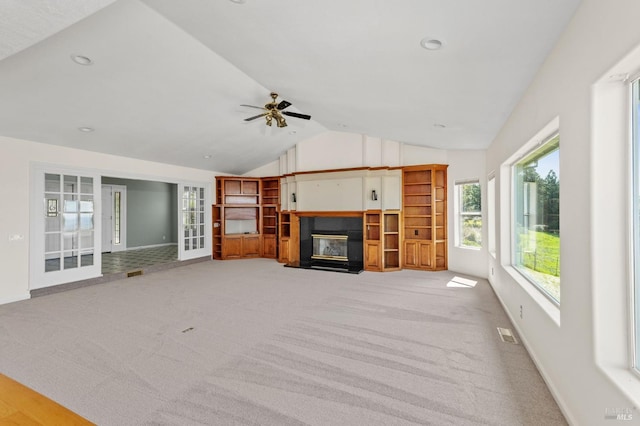 unfurnished living room featuring a ceiling fan, visible vents, a glass covered fireplace, lofted ceiling, and baseboards