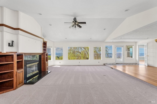 interior space featuring light carpet, ceiling fan, a fireplace, and lofted ceiling