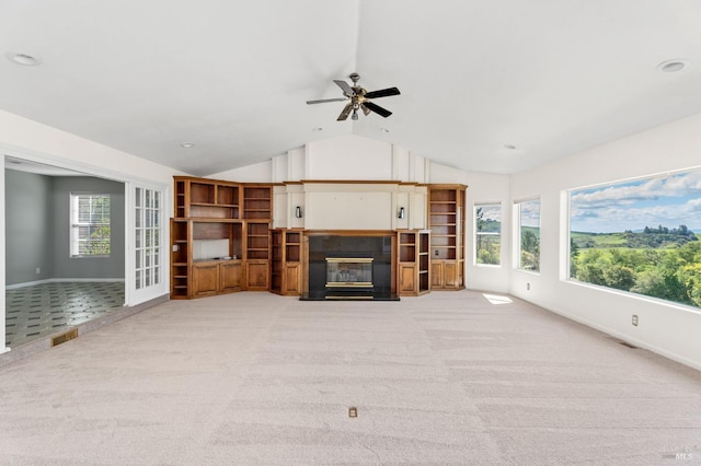 living area featuring visible vents, a ceiling fan, a fireplace with flush hearth, light carpet, and lofted ceiling