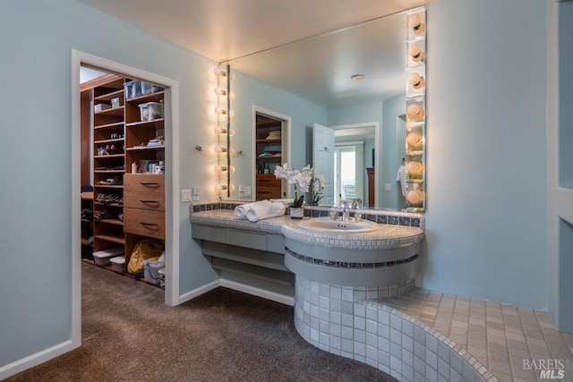 bathroom featuring vanity, baseboards, carpet, and a walk in closet