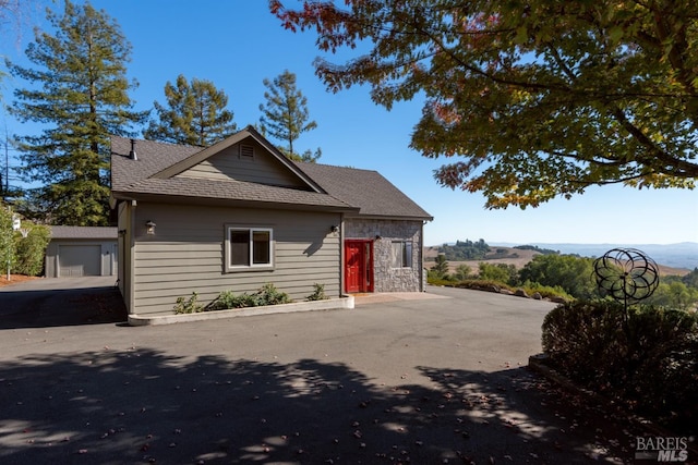 view of front of property with a shingled roof and stone siding