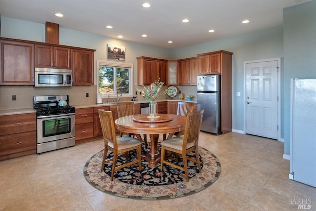 kitchen with baseboards, a sink, light countertops, appliances with stainless steel finishes, and recessed lighting