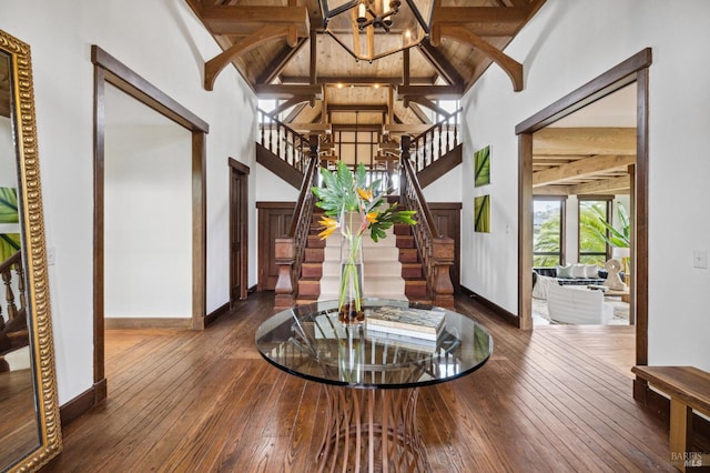 foyer featuring high vaulted ceiling, dark wood-style floors, an inviting chandelier, and stairs