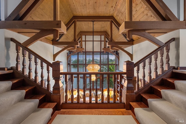 staircase featuring beamed ceiling, high vaulted ceiling, a chandelier, wooden ceiling, and wood finished floors