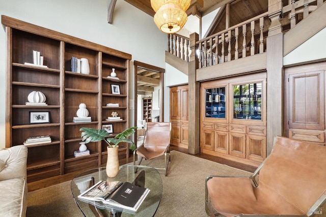 sitting room featuring beam ceiling, high vaulted ceiling, and wood finished floors