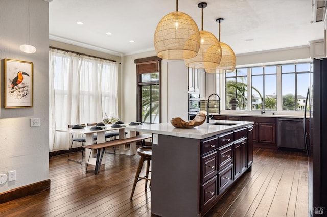 kitchen featuring light countertops, crown molding, a breakfast bar area, appliances with stainless steel finishes, and a sink