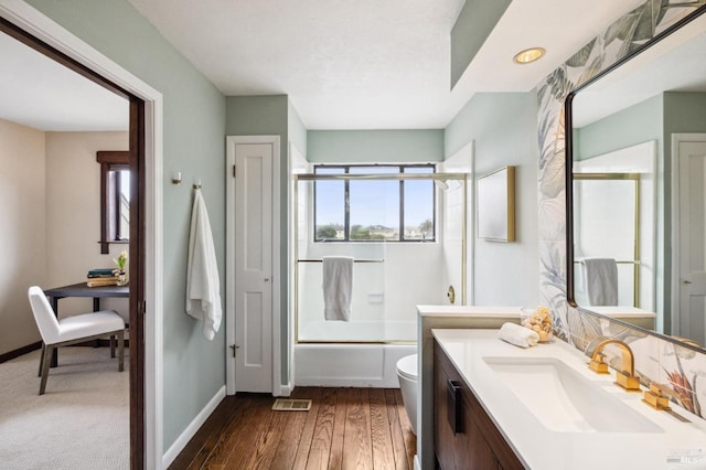 full bath featuring vanity, baseboards, combined bath / shower with glass door, and a wealth of natural light