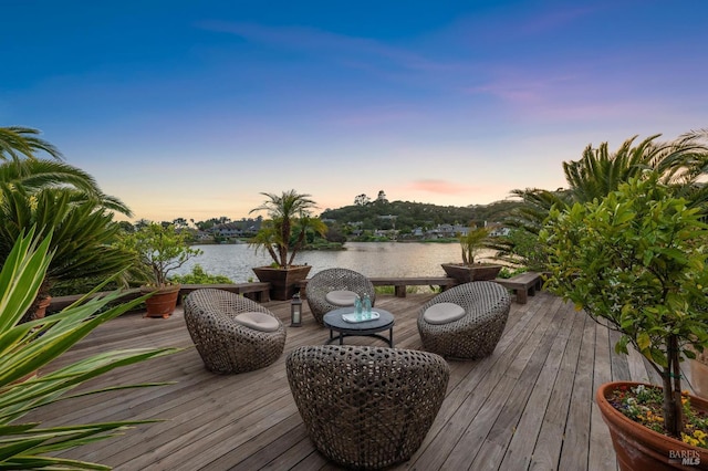 deck at dusk featuring a water view