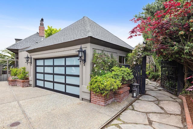 view of property exterior with roof with shingles, a chimney, driveway, an attached garage, and fence