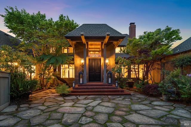 exterior space with a chimney and a shingled roof