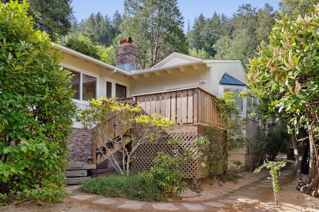 rear view of property with stairway, a chimney, and a deck