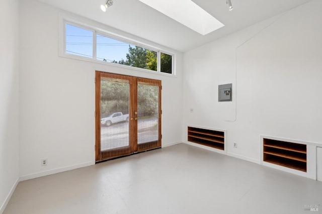 unfurnished living room featuring concrete floors, a skylight, baseboards, and french doors