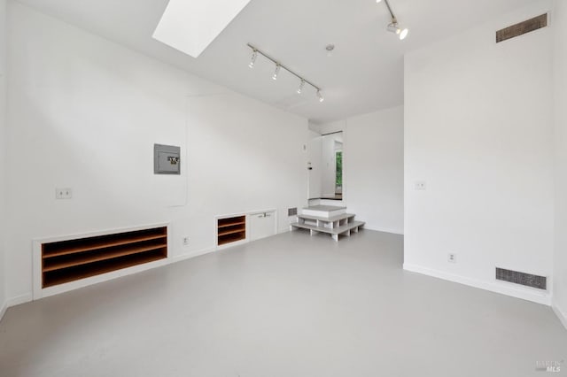 empty room featuring a skylight, track lighting, finished concrete flooring, baseboards, and visible vents