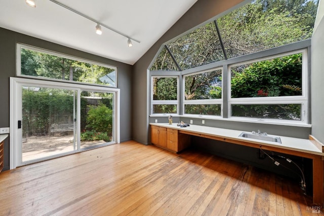 unfurnished sunroom featuring rail lighting and a sink