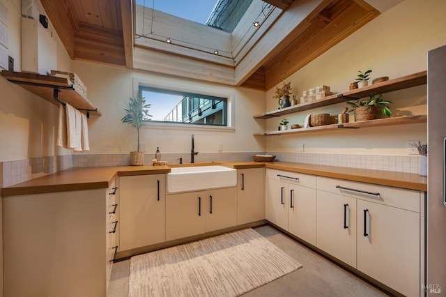 kitchen with a skylight, white cabinetry, a sink, and open shelves