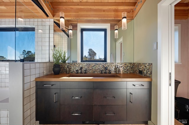 bathroom with beam ceiling, decorative backsplash, and vanity