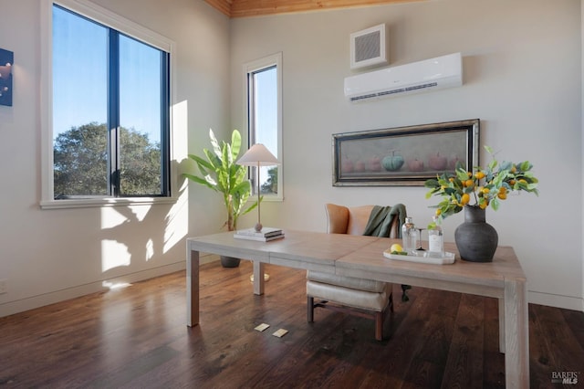 office space with a wall unit AC, wood finished floors, baseboards, and visible vents