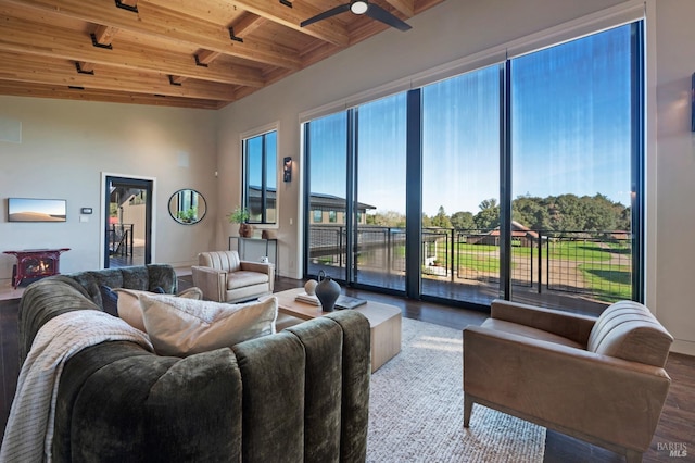 living room featuring baseboards, ceiling fan, wood ceiling, beam ceiling, and wood finished floors