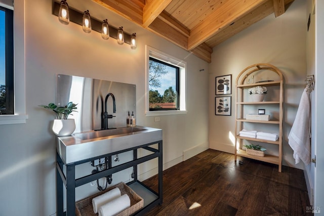 interior space featuring wooden ceiling, baseboards, beam ceiling, a sink, and wood finished floors