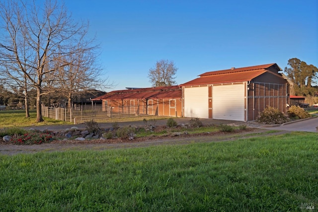 view of front of house featuring a detached garage, fence, and an outdoor structure