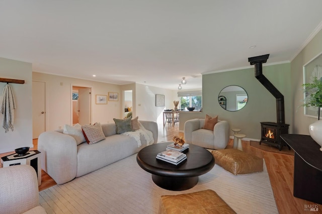 living room featuring crown molding, a wood stove, wood finished floors, and baseboards