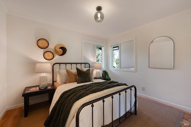bedroom featuring baseboards, crown molding, and wood finished floors