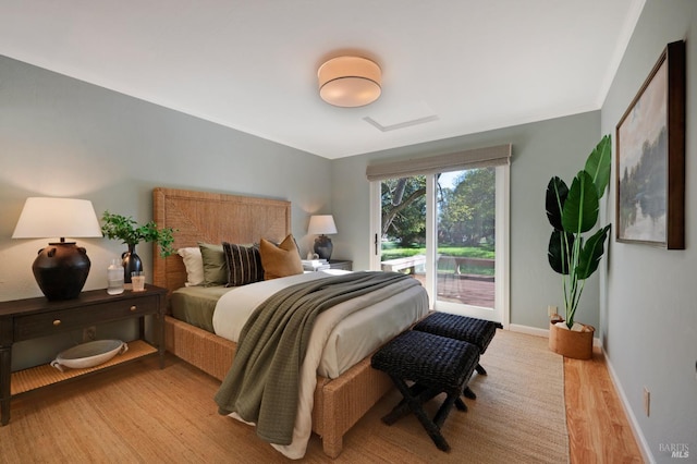 bedroom with light wood-type flooring, baseboards, and access to outside