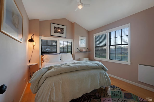 bedroom with baseboards, multiple windows, wood finished floors, and lofted ceiling