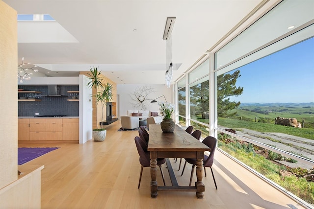 dining space with expansive windows, light wood-style flooring, and a rural view