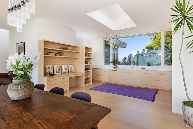 interior space with light wood-style flooring, an inviting chandelier, and a skylight