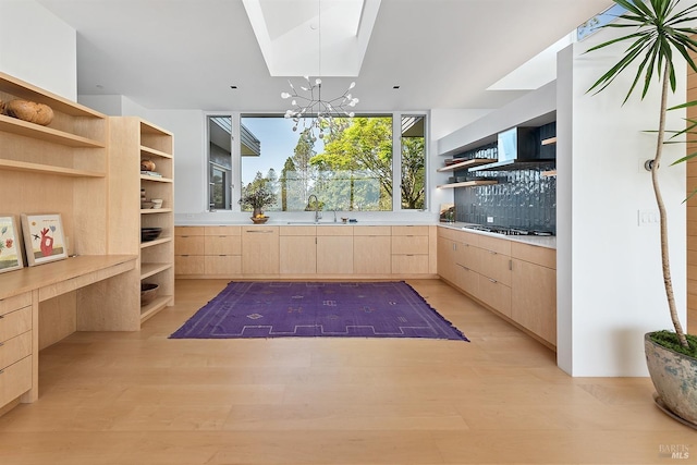 kitchen featuring light brown cabinets, open shelves, light wood finished floors, stainless steel gas stovetop, and a sink