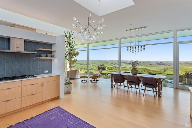 interior space featuring light brown cabinetry, light wood finished floors, backsplash, gas cooktop, and expansive windows
